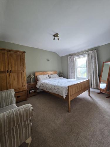 a bedroom with a bed and a chair and a window at Brook cottage in Brayton Station