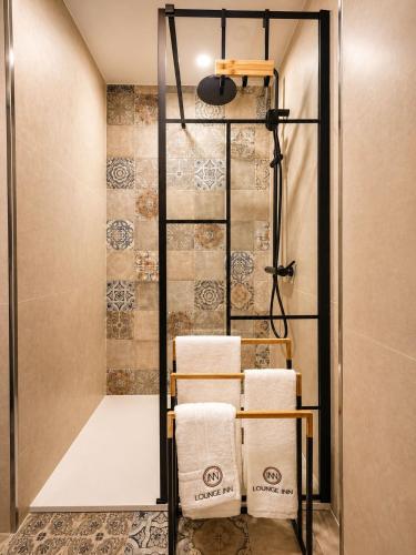 a shower with towels on a rack in a bathroom at Lounge Inn Guest House in Porto