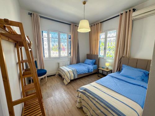 a bedroom with two beds and a ladder and windows at L'hirondelle bleue in Tunis