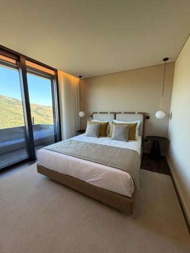 a bedroom with a large bed with a large window at Quinta Vale de Lobos in Folgosa
