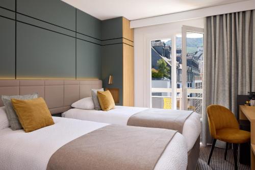 zwei Betten in einem Hotelzimmer mit Fenster in der Unterkunft Hôtel Roissy in Lourdes