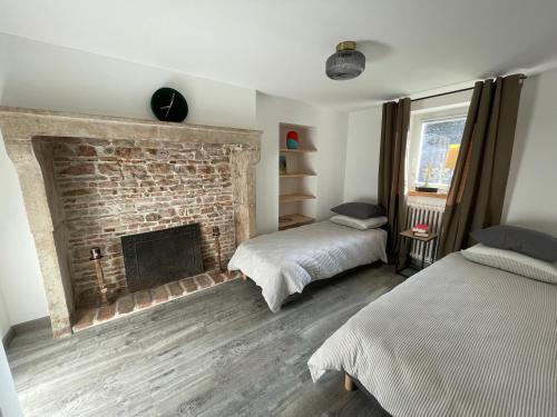 a room with two beds and a brick fireplace at Maison de campagne 110m2 in Longeault