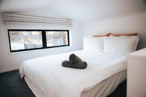 a bedroom with a white bed with a hat on it at Alpine Chalet - views, fire-pit, central, cosy in Wanaka