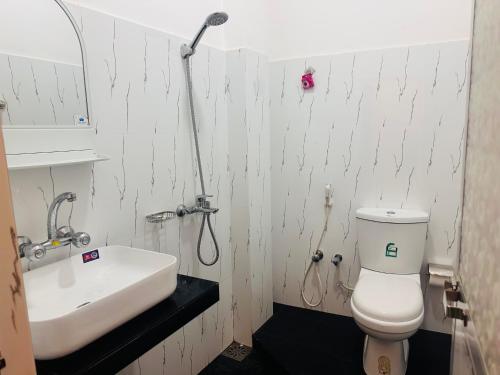 a bathroom with a white toilet and a sink at Goldern Gate in Kandy