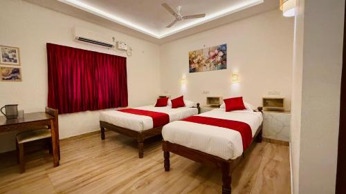 two beds in a room with a red curtain at Ayaf Homes in Pondicherry