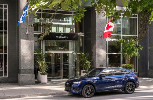 a blue car parked in front of a building at Warwick Le Crystal - Montréal in Montreal