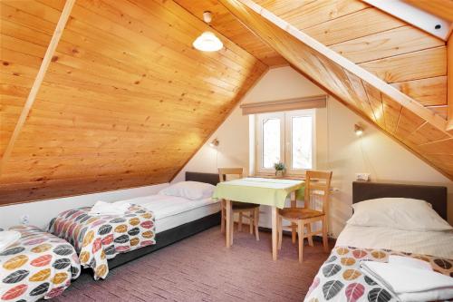 a attic room with two beds and a table at Dobra Miejscówka in Krynica Zdrój