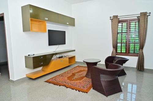 a living room with a tv and some chairs at Relaxing Villa in Mysuru! in Mysore