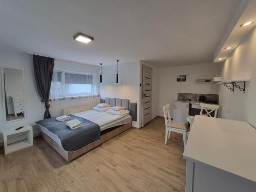 a bedroom with a bed and a desk and a kitchen at Noclegi Piaskowa 44 in Nowa Karczma