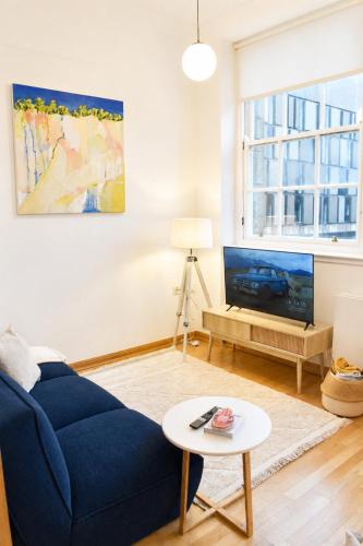 a living room with a blue couch and a tv at Luxury Historic City-Centre Flat & Free Parking in Glasgow