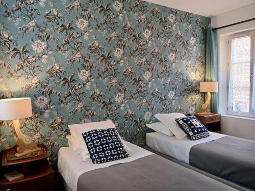 a bedroom with two beds and a wall with floral wallpaper at La Georginette in Saint-Georges-sur-Cher
