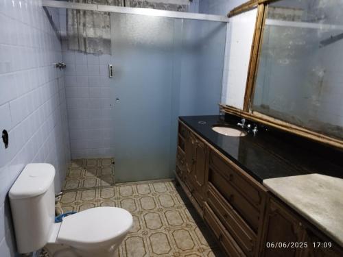 a bathroom with a white toilet and a sink at Chácara Volito in Cotia