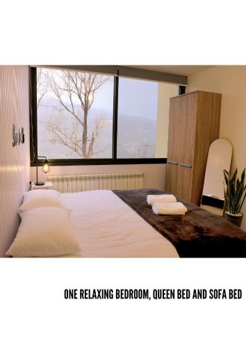 a bedroom with a bed with a large window at Domaine De Faraya F2 in Nab‘ al Maghārah