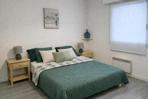 a bedroom with a bed with a green comforter at Centre ville de Sarzeau, appartement au calme avec jardinet et parking privé in Sarzeau