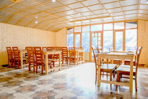a dining room with tables and chairs and windows at pristine mountain lodge in Chail