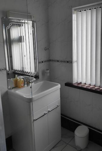a white bathroom with a sink and a mirror at Katie's Cottage in Laghy