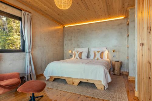 a bedroom with a white bed with a wooden ceiling at Casa do Incenso in São Roque do Pico