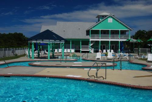 a swimming pool with a playground and a house at Hamilton Cay at Bermuda Bay by Kees Vacations in Kill Devil Hills