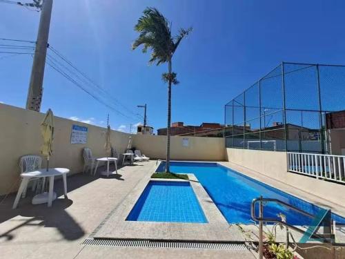 a swimming pool with a palm tree next to a building at Conforto e praticidade perto do aeroporto in Aracaju