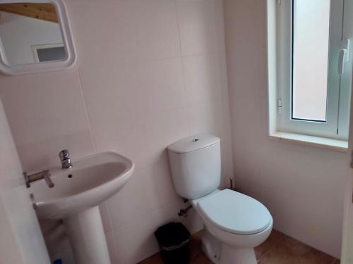 a white bathroom with a toilet and a sink at Casa do Rio Alva in Caldas de São Paulo