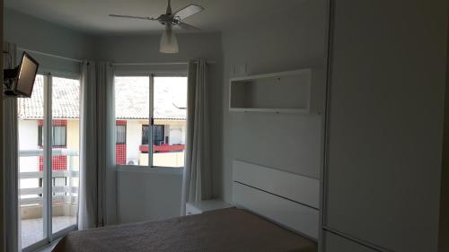 ein Schlafzimmer mit Deckenventilator und Fenster in der Unterkunft Apto Ingleses à 50mts da praia in Florianópolis