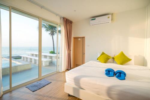 a bedroom with a bed with blue slippers on it at SunRise Beachfront Cha am in Ban Bang Ket