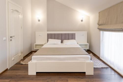 a white bedroom with a large white bed and a window at Galaktyka Hotel in Stantsiya Biskovitse
