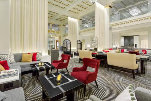 a living room with a couch and red chairs at Hilton Boston Park Plaza in Boston