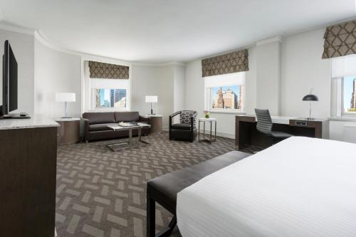 a hotel room with a bed and a living room at Hilton Boston Park Plaza in Boston