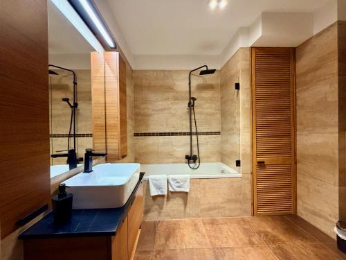 a bathroom with a tub and a white sink at Apartament Widna in Krakow
