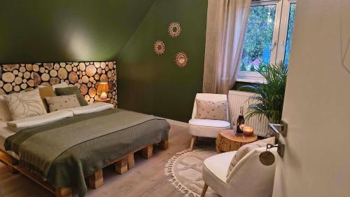 a green bedroom with a bed and a chair at Leśna Kryjówka in Trzebciny