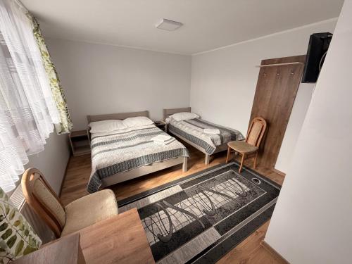 a small room with two beds and a chair at U Marzeny in Malbork