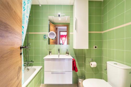 a green bathroom with a sink and a toilet at Premium Oceanside Apartment, Pool, Parking in Port Saplaya