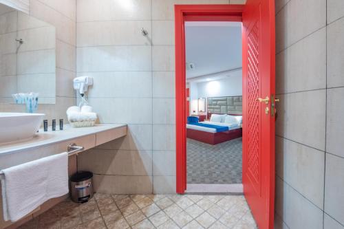 a bathroom with a red door leading to a bedroom at Denis Hotel Tbilisi in Tbilisi City