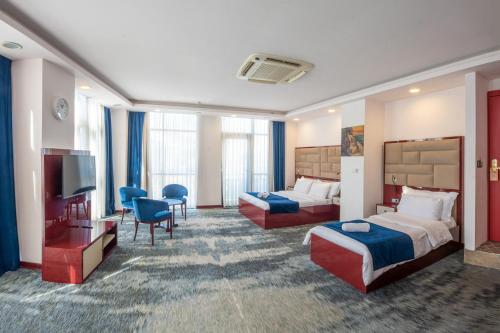 a hotel room with two beds and a flat screen tv at Denis Hotel Tbilisi in Tbilisi City