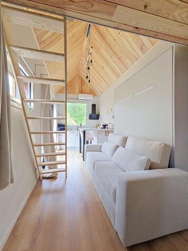 a living room with a white couch and a staircase at Maisonnette d'architecte face nature, 15min de Tours in Charentilly
