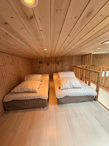 two beds in a room with a wooden ceiling at Neptuni Bed and Kitchen in Varberg