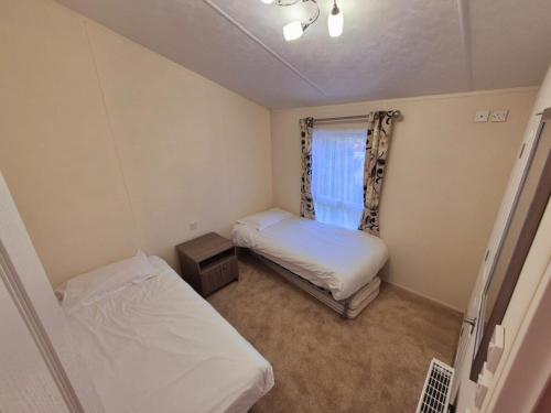 a small room with two beds and a window at Birchington Vale - Delta Lodge in Kent
