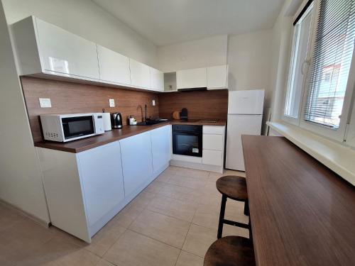 a kitchen with white cabinets and a table and a microwave at ApartmanONE in Hlohovec