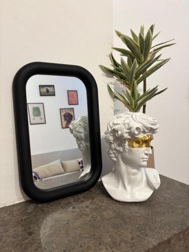 a mirror sitting on a table next to a bust at L'Orelia - confortable T2 hyper centre in Montélimar