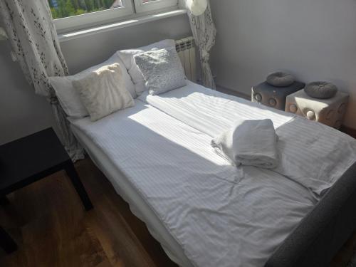 a bed with white sheets and pillows in a bedroom at Siódme niebo in Gdańsk