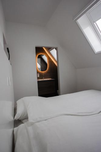 a bedroom with a white bed and a mirror at vredehof appartement in Sint Maartensbrug