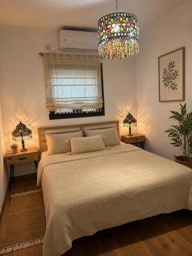 a bedroom with a large bed and a chandelier at Cozy flat near park in Netanya