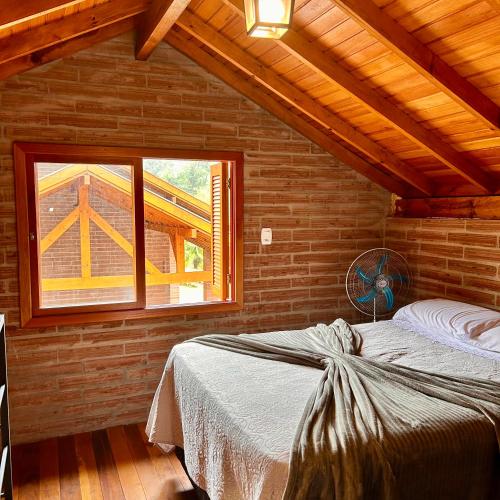 a bedroom with a bed in a room with a window at Villetta Gramado Roma in Gramado