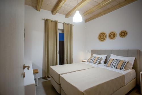 a white bedroom with two beds and a window at Mystic Harmony in Mikonos