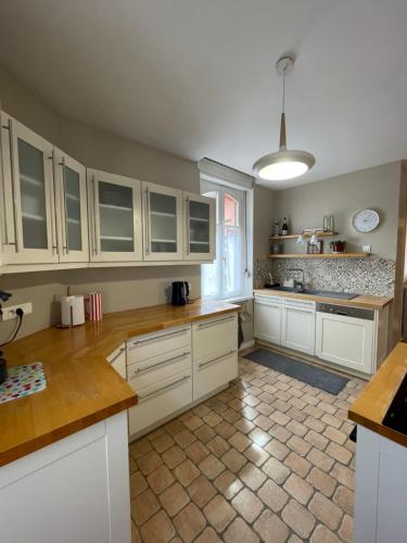 a kitchen with white cabinets and a tile floor at Le Cocon Turckheim in Turckheim