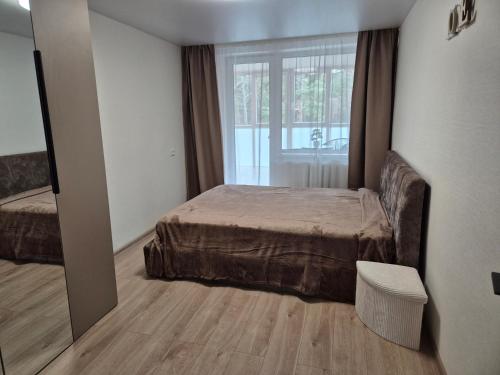 a bedroom with a bed and a large window at MV Apartament in Druskininkai