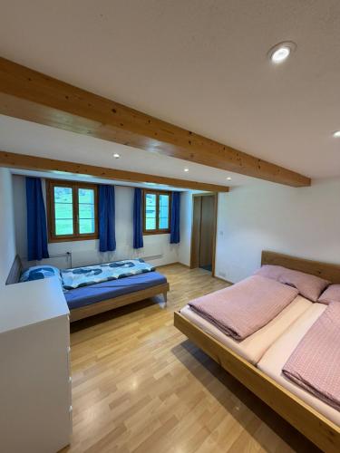 two beds in a large room with blue curtains at Ferienwohnung Bürgenblick in Kehrsiten