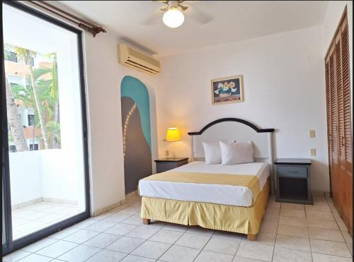 a bedroom with a bed and a large window at Hotel Costa Brava in Manzanillo
