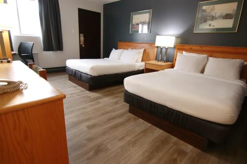 a hotel room with two beds and a desk at Colonial Inn in Brandon